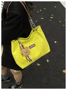 Détail du cabas en velours côtelé jaune avec breloque ours en peluche et bandoulière