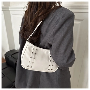 Detail of white faux leather underarm bag with silver rivet studs on female model