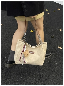 Détail du sac cabas beige en velours côtelé avec breloque ours et bandoulière chaîne