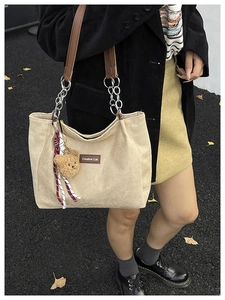 Détail du cabas en velours côtelé beige avec poignées marron et pendentif ours d'automne
