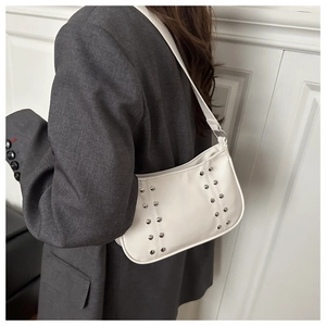 Détail du sac bandoulière en cuir blanc avec rivets métalliques et bandoulière minimaliste