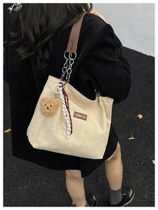 Détail du cabas en velours côtelé beige avec écusson en cuir et bandoulière en chaîne