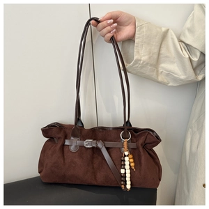 Détail d'un sac cabas en daim marron foncé avec lanière en cuir et breloque perlée tricolore