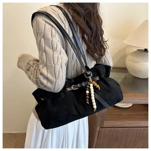 Detailed view of black suede tote bag with drawstring closure and wood bead pendant