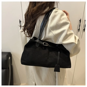 Détail d'un grand sac cabas en daim noir avec boucle métallique et étiquette en cuir