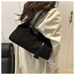 Close-up of vintage black matte leather tote bag with gold metal hardware on model