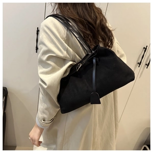 Close-up of black matte suede tote bag with leather straps on a model's shoulder