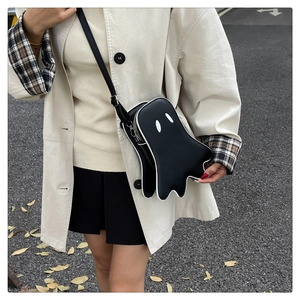 Detail of cute ghost-shaped crossbody bag with eyes and silver zipper in outdoor setting