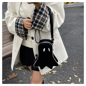 Close-up of the cute ghost-shaped crossbody bag worn over a beige checkered coat
