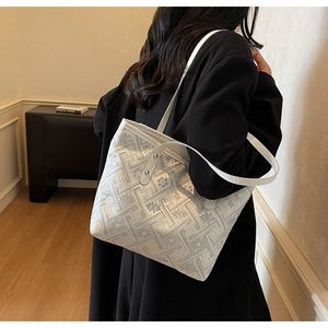 Detail showing the intricate silver floral geometric pattern on the beige tote bag
