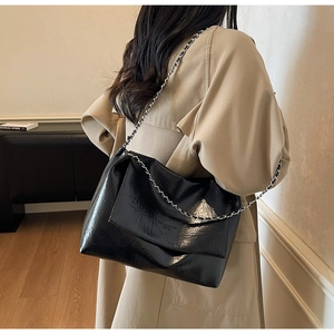 Detail of black glossy wrinkled leather shoulder bag with silver metal chain strap