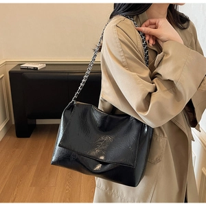 Details einer glänzenden Schultertasche aus Knitterleder mit schicker Silberkette