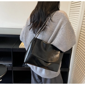 Detail of glossy black large tote bag with chain strap and natural crinkle texture finish