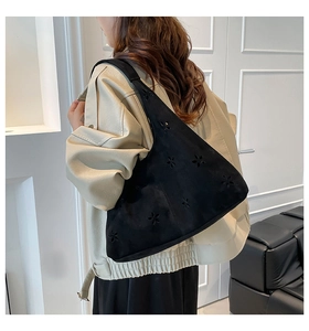 Detail view of black suede dumpling bag featuring intricate floral cut-out patterns
