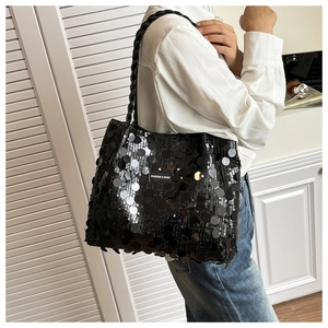 Detail of black sequined tote bag featuring woven rope handle and leather fashion label