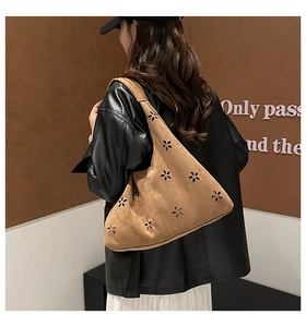 Detail of laser-cut petal pattern on brown suede tote bag worn by a model