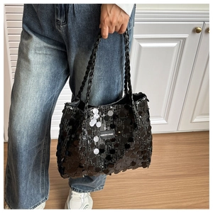 Detail of black sequined tote bag with woven handles and fashion logo patch