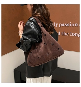 Detail of dark brown suede hobo bag featuring decorative cutout flower patterns