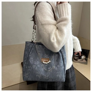 Dettaglio borsa tote in jacquard blu con decoro di perle e tracolla a catena