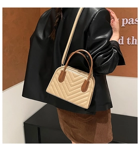 Detail of beige V-quilted handbag with dark brown handle and leather strap texture