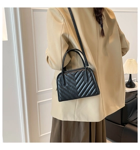 Detail of black chevron quilted handbag showing slim shoulder strap and leather texture