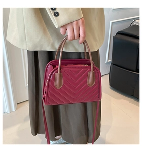 Macro detail of wine red quilted shell bag with elegant V-pattern and brown handles