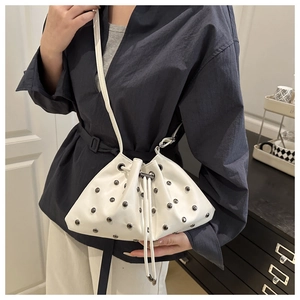 Detail view of white drawstring bucket bag with silver metal studs and leather strap