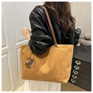 Detail view of large brown suede tote bag with leather strap on model's shoulder