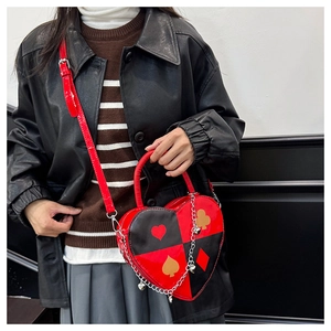 Detail view of heart-shaped handbag with poker suit prints and silver chain pendant