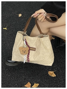 Détail du sac fourre-tout beige en velours côtelé avec anses en cuir et breloque ours