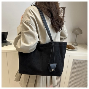 Detail of minimalist black matte tote bag with thin straps and triangle charm detail