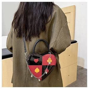 Model wearing heart-shaped crossbody bag with playing card motifs and chain strap