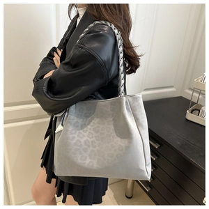 Close-up of a leopard print tote bag with thick silver-grey braided handles and ribbon detail