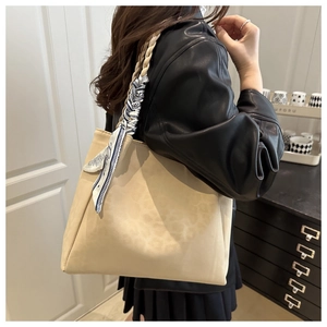 Beige suede tote bag detail with woven strap and decorative blue floral scarf