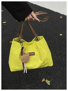 Détail du sac fourre-tout matelassé jaune avec lanières en cuir brun et ours en peluche