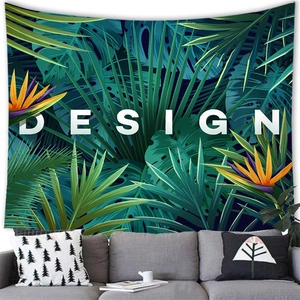 Tropical monstera leaf wall tapestry with white DESIGN text over a modern grey sofa