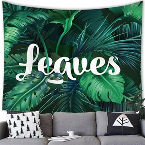 Detail of tropical monstera leaf tapestry with Leaves text above a grey sofa