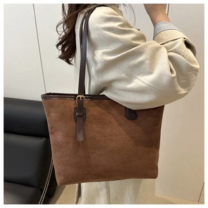 Detail of a large brown suede tote bag with adjustable leather strap and golden hardware