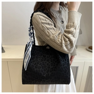 Detail of black leopard print tote bag with woven handles and decorative Paris scarf