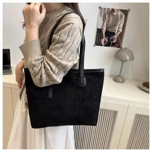 Détail de la texture d'un grand sac cabas en daim noir avec bandoulière fine élégante