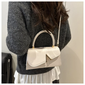 Schicke weiße strukturierte Handtasche mit goldener V-Schnalle an der Schulter des Models