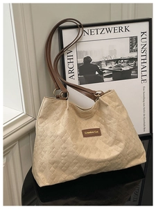 Dettaglio della borsa shopper beige trapuntata con manici marroni, tessuto testurizzato e stile.