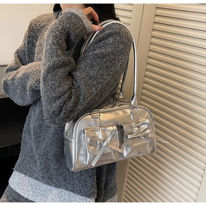 Sac bandoulière argenté Y2K avec poches à nœuds et fini brillant porté par un mannequin