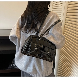 Détail d'un sac bandoulière en cuir verni noir avec nœuds porté par un mannequin