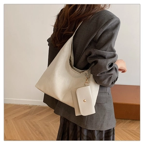 Minimalist beige suede crescent hobo bag with mini pouch shown in professional commute scene