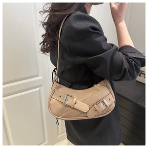 Detail view of beige crescent bag featuring double silver metal buckles on the front strap