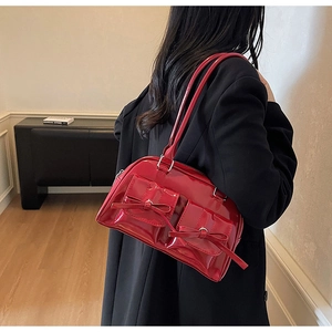 Detail of red patent leather handbag with bow accents and glossy mirror finish