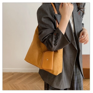 Detail of a ginger suede tote bag styled with a gray suit for a minimalist commute look