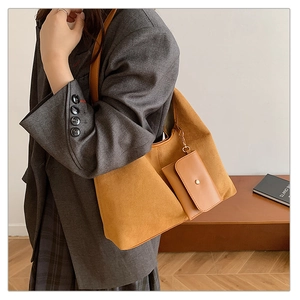 Close-up of ginger suede tote bag with small matching pouch on a grey blazer model