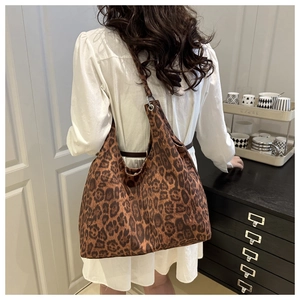 Close-up of stylish leopard print tote bag worn on shoulder in a cozy interior setting